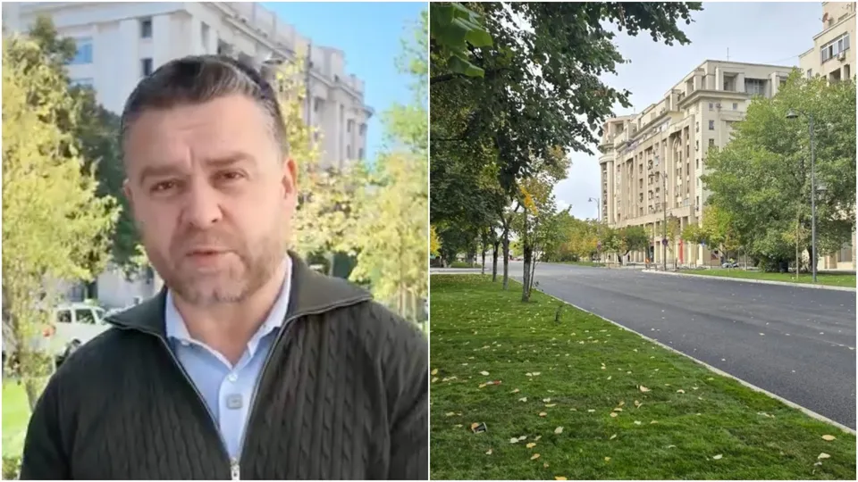 Un bărbat cu barbă și veste neagră stă în prim-plan, în timp ce în partea dreaptă se vede o stradă asfaltată lângă un gard de iarbă verde.