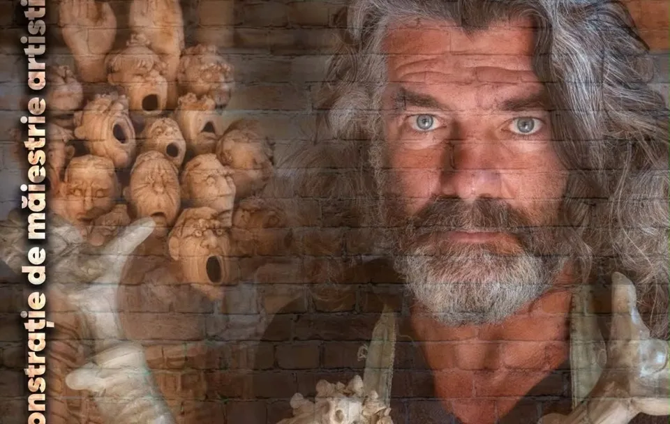 Un bărbat cu părul și barba gri privește spre cameră, având în fundal numeroase sculpturi ceramice în formă de capuri umane.