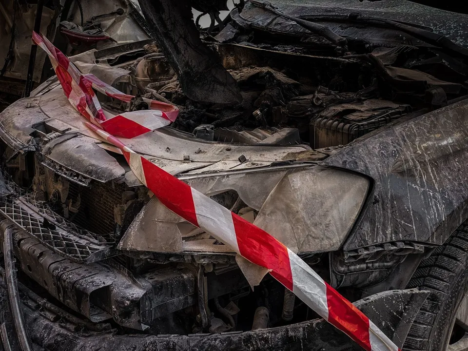 Un autoturism distrus și deformat este marcat cu o bandă de avertizare albă și roșie.