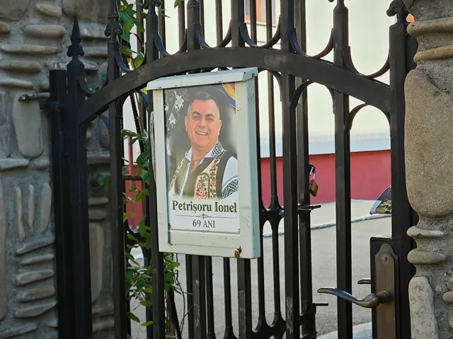 Un cadru cu un portret încadrat într-o cutie albă, afișat pe o poartă metalică neagră.