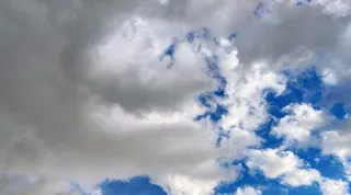 Norii albi și cenușii acoperă parțial un cer albastru.
