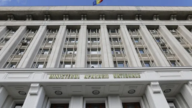 Fațada unei clădiri înalte de culoare gri cu numeroase ferestre și un steag deasupra acoperișului.