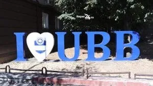 Literele albastre "I", "UBB" și un simbol de inimă albă cu un emblema albastră sunt dispuse pe un teren cu nisip.