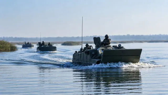 Două vehicule militare de culoare închisă navighează pe un lac, lăsând urme de spumă albă în urmă pe apă.