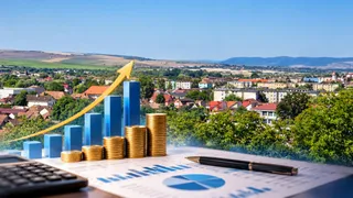 Un grafic cu săgeată galbenă ascendentă, coloane albastre și stive de monede aurii sunt suprapuse peste o imagine cu o zonă urbană și dealuri.