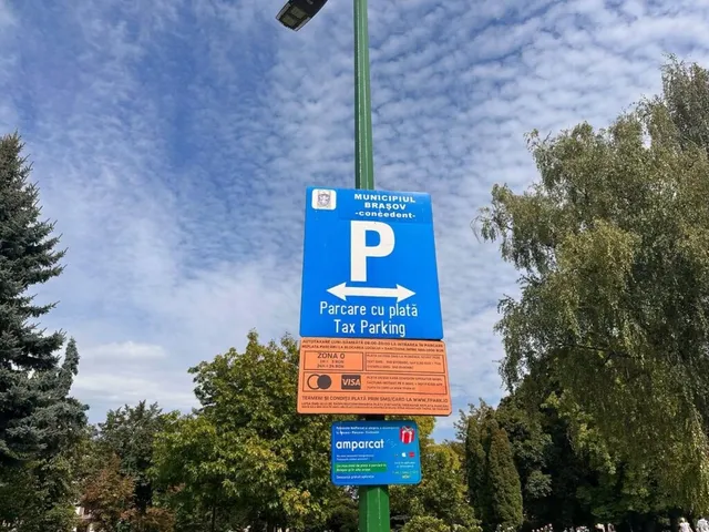 Un semn albastru cu litera P albă și textul parcare cu plată este montat pe un stâlp verde sub un cer cu nori subțiri.