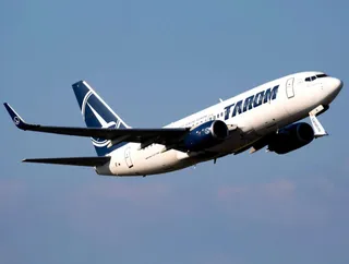 Un avion alb cu însemne albastre zboară pe un cer albastru.