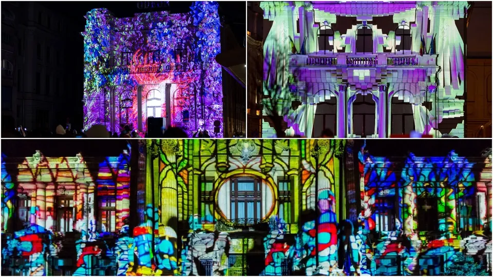 Proiecții colorate de tip video mapping sunt vizibile pe fațadele unor clădiri de noapte, în prezența unor siluete de oameni în prim-plan.