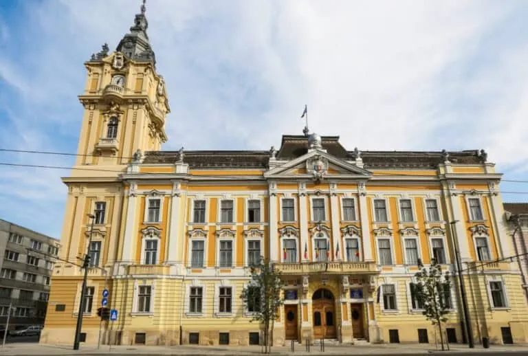O clădire galbenă cu arhitectură clasică și un turn înalt sub un cer înnorat.