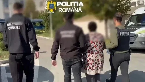 Patru persoane merg pe un drum, dintre acestea două poartă uniformă neagră cu inscripții albe și una poartă un tricou cu modele colorate.