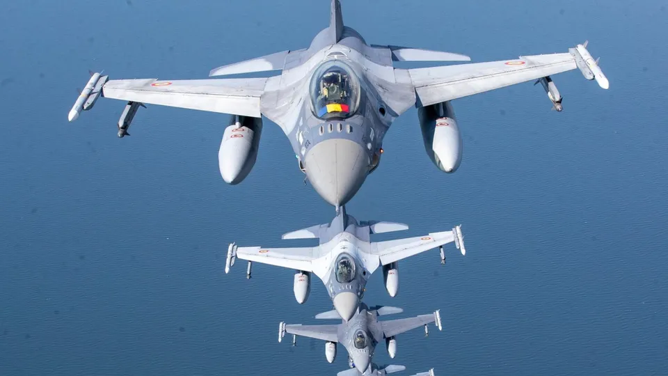 Trei avioane de vânătoare gri zboară în formare verticală pe un fundal de cer albastru.