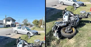Un autoturism gri și o motocicletă avariată sunt situate pe marginea unui drum asfaltat lângă o zonă cu iarbă.
