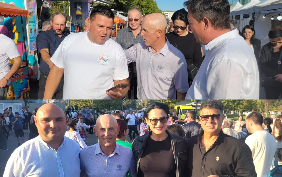 Un grup de persoane stă în picioare afară, în timp ce unii privesc spre un telefon mobil.