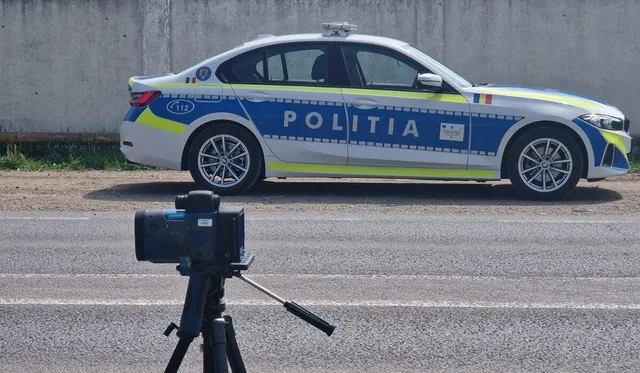 O mașină de poliție albă și albastră cu inscripția POLITIA este parcată pe un drum lângă un aparat de măsurare montat pe un trepied.