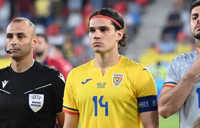 Un bărbat cu o bandană roșie și un tricou galben cu numărul 14 stă lângă un arbitru îmbrăcat în negru.