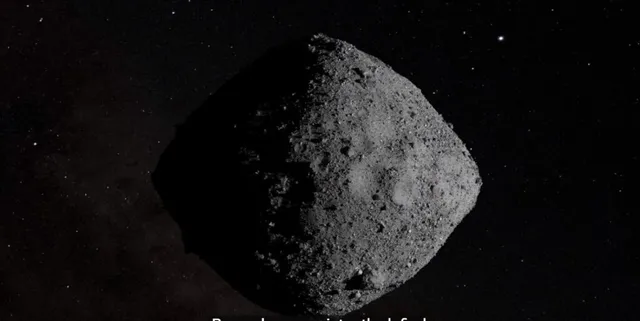 Un asteroid de formă neregulară și suprafață craterată este vizibil pe un fundal negru presărat cu puncte luminoase mici.
