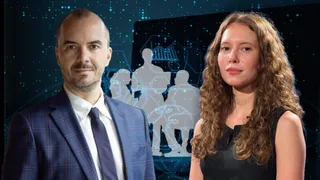 Un bărbat cu sacou și cravată stă lângă o femeie cu părul lung și creț în fața unui ecran digital cu siluete umane.