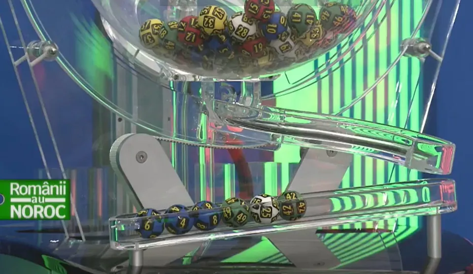 Numere rotunde colorate cu cifre negre sunt așezate într-un recipient transparent și pe o traiectorie de plastic sub un fundal cu linii verzi.