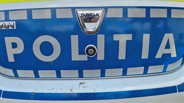 Un prim-plan al unei grilaje de radiator albastre de pe un vehicul, pe care este aplicat logo-ul Dacia și textul POLITIA.