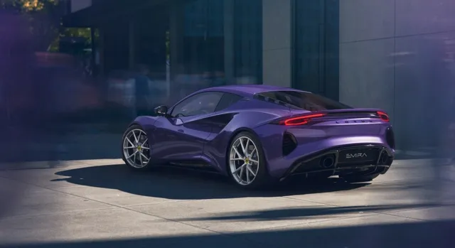 Un automobil sportiv de culoare mov este parcat pe o suprafață pavată în fața unei clădiri moderne sub lumina soarelui.