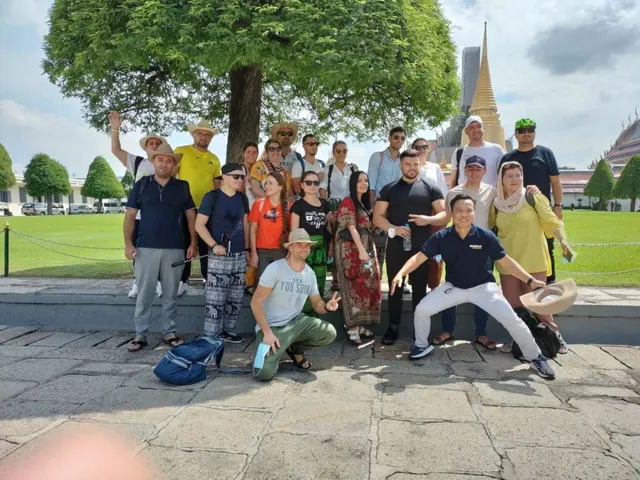 Un grup de oameni stă pozat în fața unui copac mare și a unui stup de aur sub un cer înnorat.
