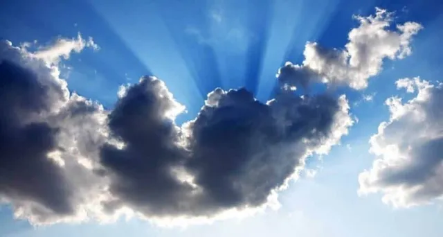 O imagine a cerului albastru intens cu nori gri și albi, din care se izbesc raze de soare puternice.