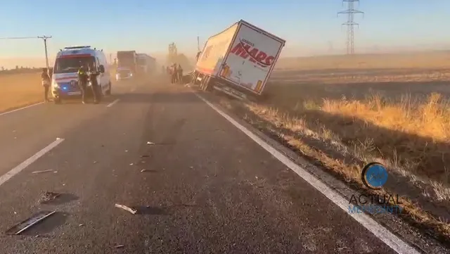 Un camion alb cu inscripții roșii este înclinat pe marginea unei drumuri asfaltate lângă o ambulanță și un autotren în lumină naturală de seară.