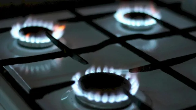 Trei arzătoare de pe o plită de gătit sunt aprinse cu flăcări albastre.