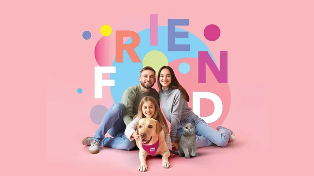 O familie formată din doi adulți și o copilă stă pe un fundal roz alături de un câine și o pisică.
