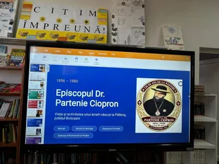 Un ecran de monitor afișează un text pe fundal albastru lângă un portret circular al unui bărbat cu barbă și pălărie neagră.