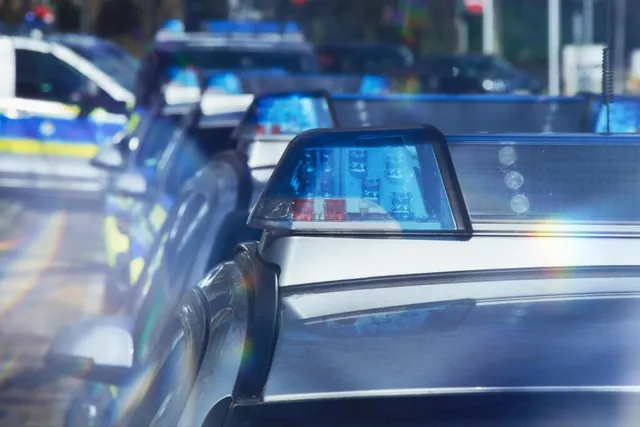 Mai multe mașini de poliție cu lumini albastre aprinse sunt parcate pe un drum, fiind surprinse dintr-un unghi lateral apropiat.