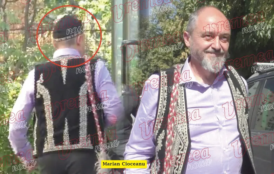 Un bărbat cu barbă și vestă tradițională neagră stă în picioare lângă un alt bărbat care poartă vestă tradițională și este văzut din spate.