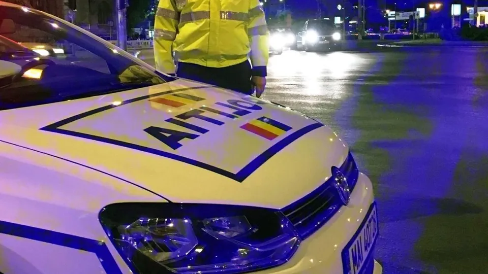 Un vehicul alb cu inscripția Jandarmeria pe capotă este parcat pe un drum asfaltat noaptea, lângă un vehicul de serviciu.