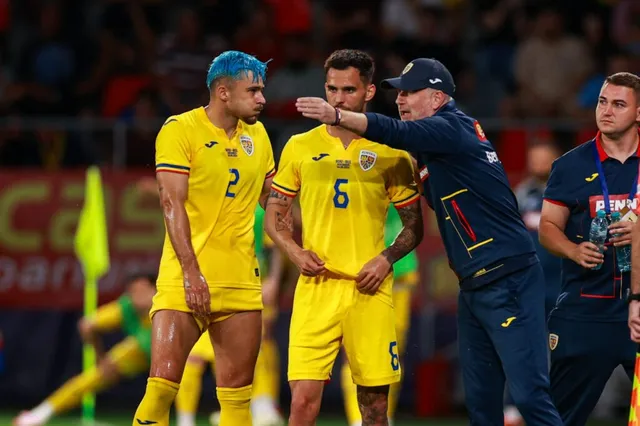 Trei bărbați stau pe un teren de fotbal, doi purtând echipamente galbene și unul purtând o șapcă și un costum sportiv albastru.