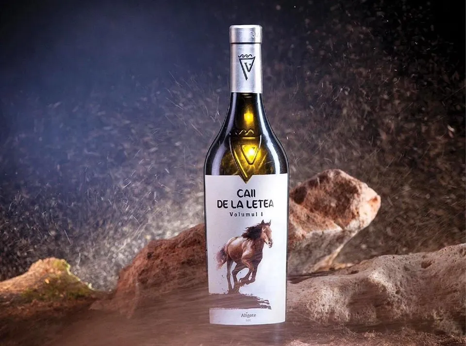 O sticlă de vin cu etichetă albă ce prezintă un cal galopând pe un fundal de roci într-un mediu întunecat și prăfuit.