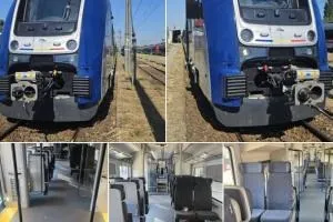 Un tren albastru și gri este oprit pe șine, iar interiorul vehiculului prezintă scaune gri dispuse pe rânduri lângă un culoar central.