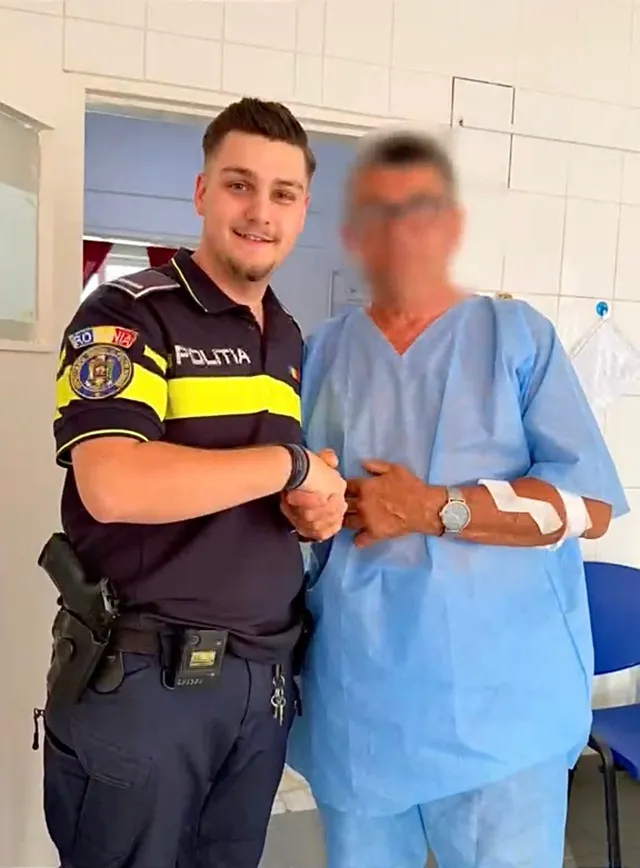 Un bărbat în halat medical albastru strânge mâna unui agent de poliție îmbrăcat în uniformă în timpul unei poze de tip portret.