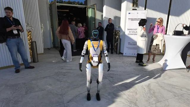 Un robot humanoid cu corp alb și detalii galbene stă în picioare pe o suprafață de marmură lângă un grup de oameni.