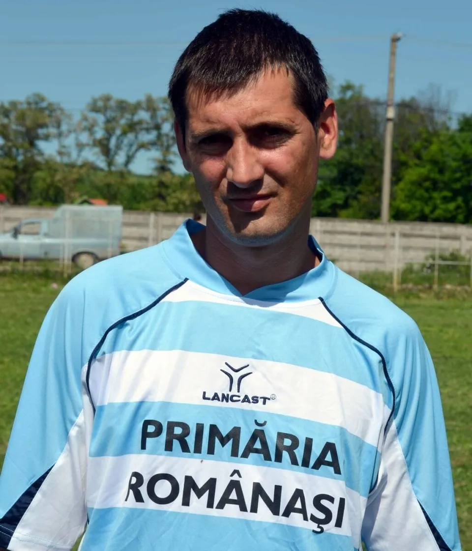 Un bărbat cu părul scurt poartă un tricou sportiv albastru și alb cu inscripția Primăria Românași.