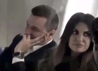 Un bărbat cu mâna la față și o femeie cu părul lung și întunecat stau unul lângă celălalt.