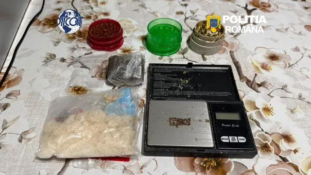 O cântar electronic neagră, un sac transparent cu o substanță albă, un sac mic gri și câteva recipiente colorate sunt așezate pe o față de masă.