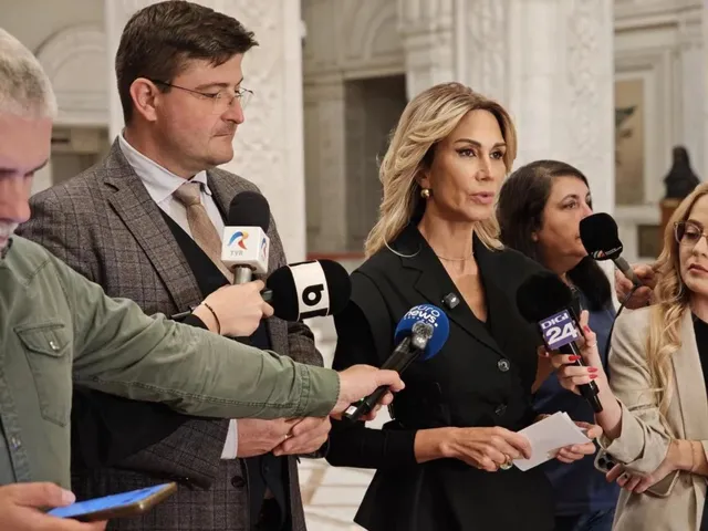 O femeie cu părul blond și o femeie cu părul închis încadrează mai mulți bărbați care țin microfoane în fața lor.