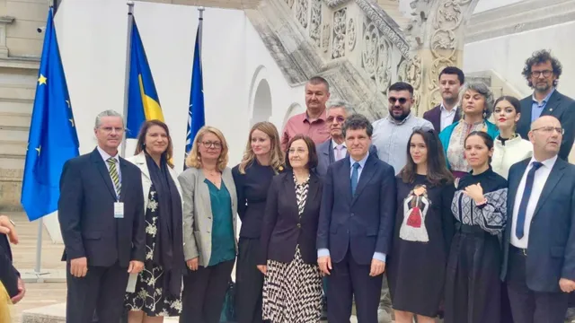 Un grup de persoane îmbrăcate în haine office stă în rând în fața unei clădiri albe cu scări și steaguri colorate.
