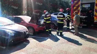 Pompieri în echipament de protecție și un bărbat stau lângă un autoturism roșu cu capota deschisă lângă un vehicul de intervenție.