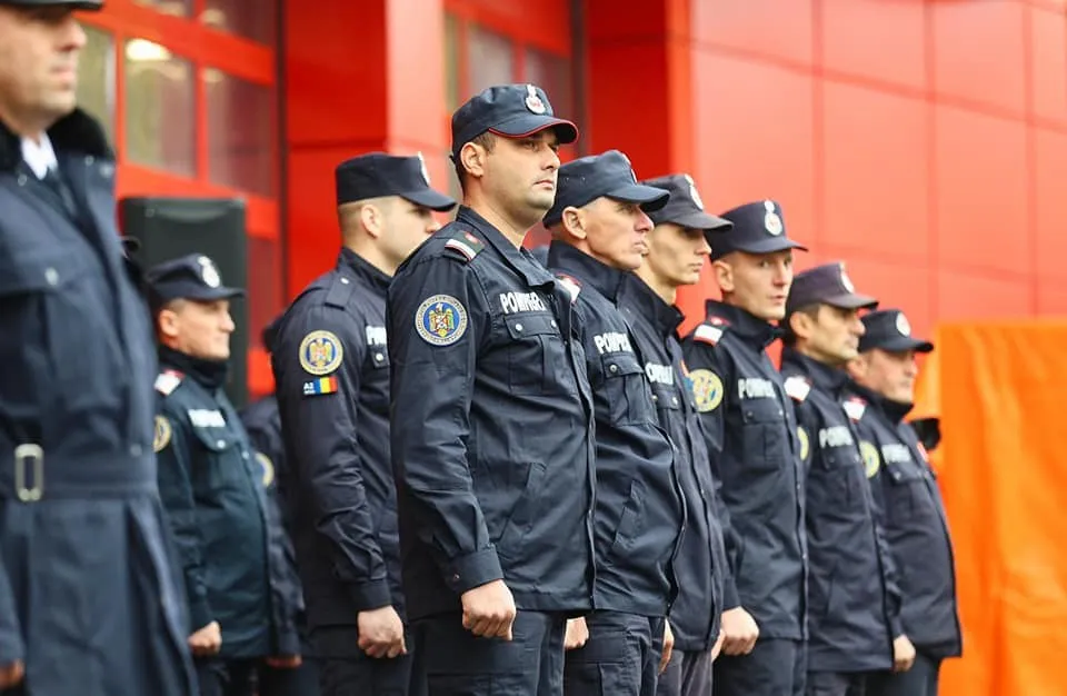 O linie de bărbați în uniforme de serviciu închise și căpițe stau în picioare, poziționați unul lângă altul.