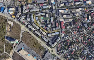 O vedere aeriană a unei zone urbane cu clădiri, străzi, drumuri și vegetație.