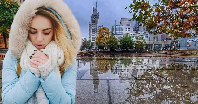O femeie cu o haină cu blană și o eșarfă albă stă într-un spațiu urban cu clădiri și reflexii în apă pe sol.