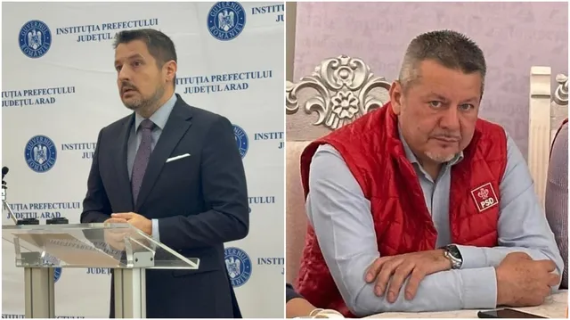Un bărbat în costum și cravată stă în spatele unui podium, iar un alt bărbat cu vestă roșie stă la o masă.