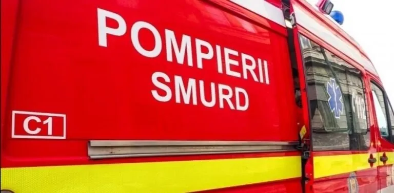 Un vehicul de serviciu roșu prezintă inscripții albe cu textul POMPIERII SMURD pe lateralul său.