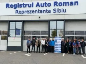Un grup de persoane stă în rând în fața unei clădiri cu inscripția Registrul Auto Roman Reprezentanta Sibiu.